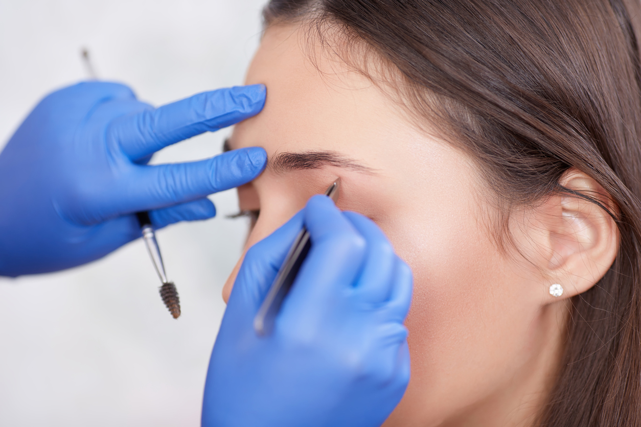 Professional in gloves plucking eyebrows for female